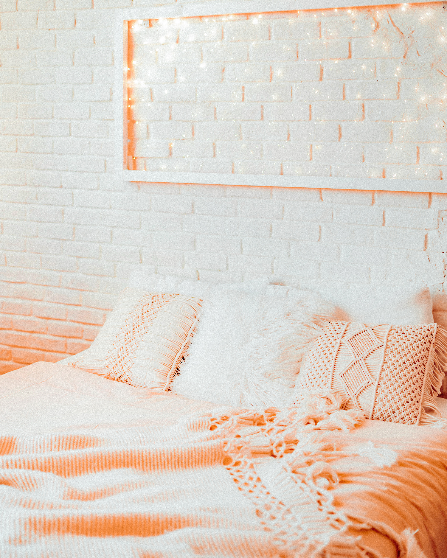 Light panel made of garlands in a white frame above the bed. Cozy modern bright bedroom. Winter Christmas interior.