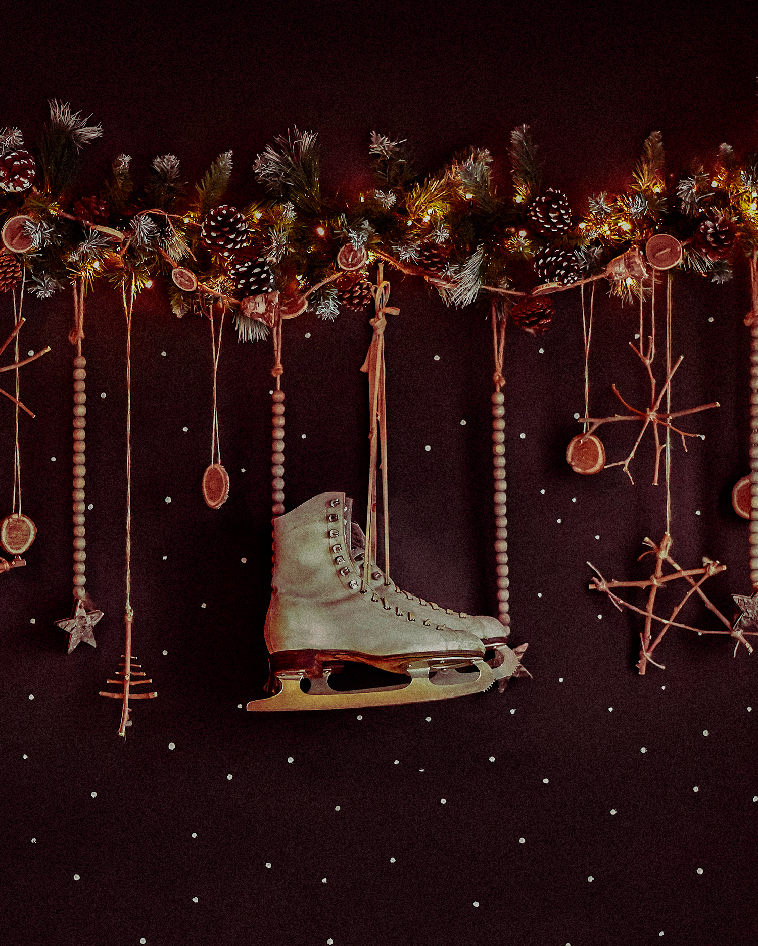 Christmas decorations on a dark wall, Happy Holiday. The wall is decorated with a garland with ate tree branches and white skates. Expectations of winter.