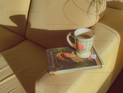 Jane Austen book and cup of tea on a couch