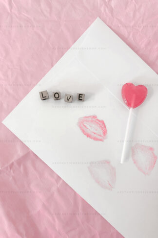 Aesthetic image of flatlay with love letter and heart shaped lollipop